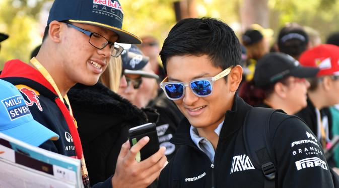 Pembalap Manor Racing, Rio Haryanto berbincang dengan penggemarnya jelang debut pada ajang Formula 1 di GP Australia, Melbourne, Minggu (20/3). Akibat mendapat penalti, Rio Haryanto harus memulai Grand Prix Australia dari posisi buncit. (Paul Crock/AFP)