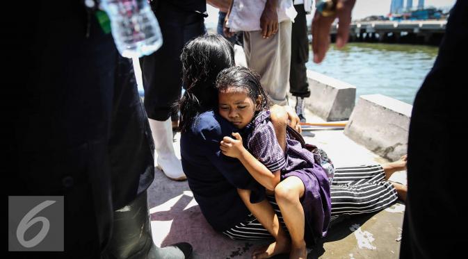 Seorang anak kecil yang terjatuh ke laut dipeluk ibunya di dermaga Muara Angke, Jakarta, Kamis (24/3). Akibat kelalaian ibunya seorang anak tercebur ke laut dan langsung di selamatkan warga dan prajurit TNI AL. (Liputan6.com/Faizal Fanani)