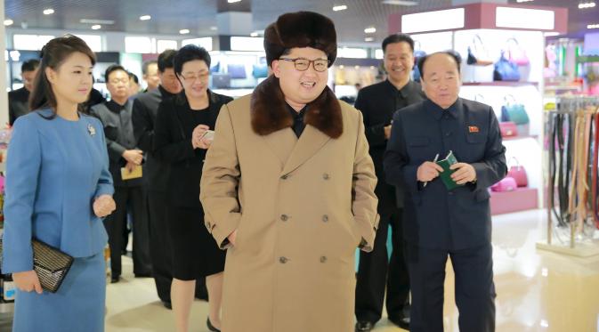 Pemimpin Korea Utara, Kim Jong-un berjalan sambil tersenyum mengunakan jaket dan topi tebal saat mengunjungi pusat perbelanjaan Mirae Shop yang baru dibangun di kompleks Mirae Shop di Korea Utara (28/3). (REUTERS/KCNA)