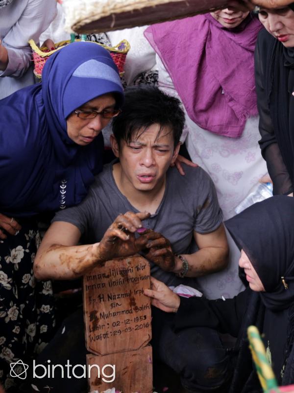 Raut muka kesedihan Ariel sambil memegang nisan Ayahnya. Air mata juga tak mampu dibendung. (Adrian Putra/Bintang.com)