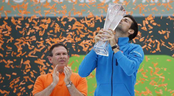 Novak Djokovic mencium piala Miami Open usai memastikan diri tampil sebagai juara, MInggu (3/4/2016)