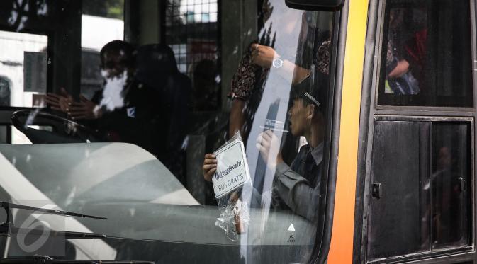 Petugas memasang tanda "Transjakarta Bus Gratis" di Jakarta, Selasa (5/4). Dinas Perhubungan dan Transportasi DKI Jakarta sudah menyiapkan ratusan bus tambahan gratis dalam rangka uji coba penghapusan kebijakan three in one. (Liputan6.com/Faizal Fanani)