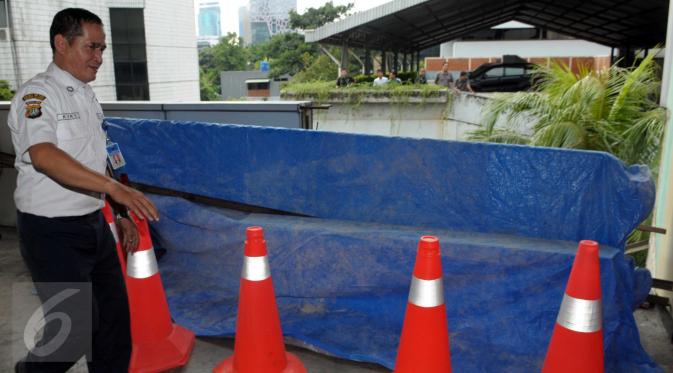 Petugas menutupi lokasi jatuhnya mobil Toyota Kijang warna merah marun dari lantai 3 Gedung Migas, Jakarta, Selasa (5/4). Mobil itu menabrak dinding pembatas di lantai 3 dan kemudian jatuh terbalik. (Liputan6.com/Helmi Affandi)