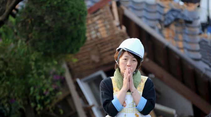 Seorang warga Jepang bersedih usai rumahnya hancur akibat gempa bumi di kota Mashiki, Prefektur Kumamoto, Jepang selatan, Sabtu (16/4). Gempa berkekuatan 6,4 SR itu menewaskan sembilan orang dan 760 lainnya terluka. (REUTERS/Kyodo)