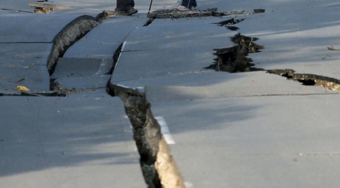 Penduduk setempat melihat jalan yang terbelah dua akibat gempa bumi yang menghantam kota Mashiki, Prefektur Kumamoto, Jepang selatan, Sabtu (16/4). Gempa berkekuatan 6,4 SR itu menewaskan sembilan orang dan 760 lainnya terluka. (REUTERS/Kyodo)