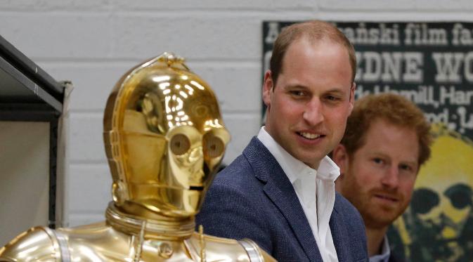 Pangeran William dan Harry melihat C3P0 droid saat mengunjungi studio pembuatan film Star Wars di Pinewood Studios, London, (19/4). Pangeran Inggris itu berkeliling Pinewood untuk mengunjungi workshop produksi film Star Wars (REUTERS/Adrian Dennis/Pool)