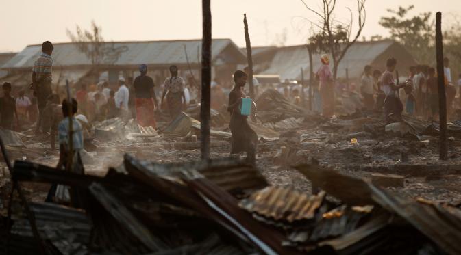 Orang-orang berdiri di antara puing-puing setelah kebakaran sebuah kamp bagi pengungsi Muslim Rohingya di negara bagian Rakhine, Myanmar, Selasa (3/5). Kebakaran menghancurkan 50 hunian sementara dalam kamp bagi pengungsi asing. (REUTERS/Soe Zeya Tun)