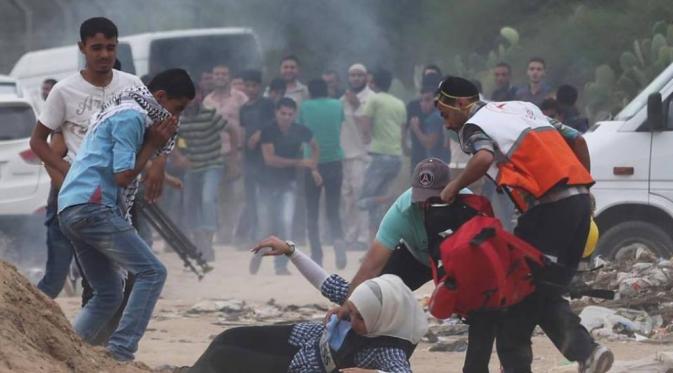 Jurnalis perempuan terjatuh ditengah kepungan bom asap. (Foto:REUTERS/Ibraheem Abu Mustafa) 