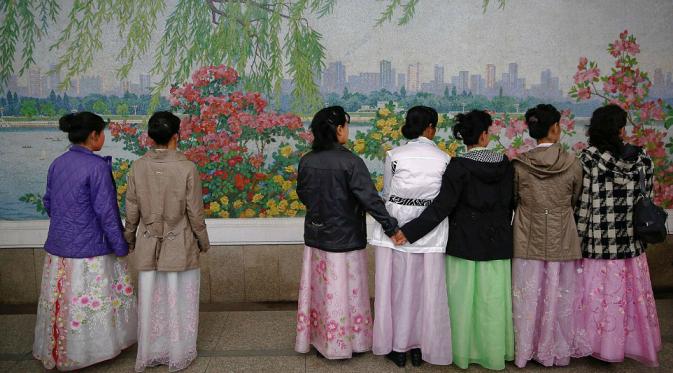 Wanita mengenakan pakaian tradisional menunggu kereta datang (Reuters)