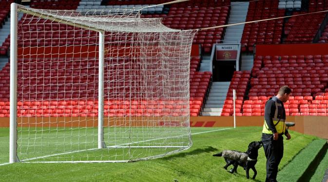 Petugas keamanan bersama anjing pelacak bom terlihat menyisir beberapa bagian stadion Old Trafford setelah ditemukan paket mencurigakan menjelang laga Manchester United melawan Bournemouth, Minggu (15/5/2016). (AFP/Oli Scarff).