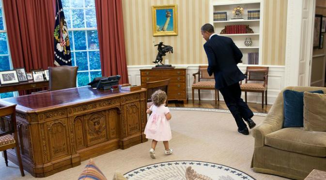 Obama tampak bermain dengan seorang gadis kecil (Pete Souza).