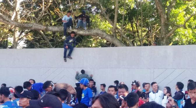 Para bobotoh Tasikmalaya nekat memanjat pohon dan melompat untuk masuk ke Stadion Wiradadaha, menyaksikan laga Persikotas Tasikmalaya melawan Persib Bandung, Sabtu (4/6/2016). (Bola.com/Permana Kusumadijaya)