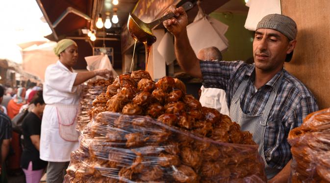 Pedagang menambahkan madu pada Chebakia, kuliner asli dari Maroko, yang dijajakan di Ibu Kota Maroko, Rabat, 6 Juni 2016. Kehadiran penganan ini menandai datangnya bulan Ramadan atau peristiwa penting. (Fadel SENNA/AFP)