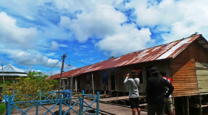 Sejumlah wisatawan tengah mengabadikan rumah panjang di Dusun Meliau, Desa Melemba, Kecamatan Batang Lupar, Kabupaten Kapuas Hulu, Kalimantan Barat. (Liputan6.com/Rita Ayuningtyas)
