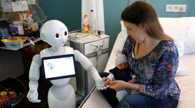 Robot humanoid bernama Pepper berdiri di samping seorang ibu dan bayinya yang baru lahir di rumah sakit AZ Damiaan di Ostend, Belgia (16/6). Robot dirancang atau dibuat untuk mengurus pasien yang datang ke rumah sakit ini. (REUTERS / Francois Lenoir)