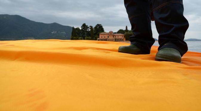 Seorang pria berdiri di atas The Floating Piers. Sumber : theweather.com