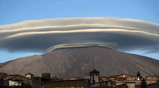 Awan lenticular yang terlihat di Sicily, Italia, terbentuk akibat adanya tiupan uap air melewati puncak gunung dan menetes pada sisi lain (Dailymail.com).