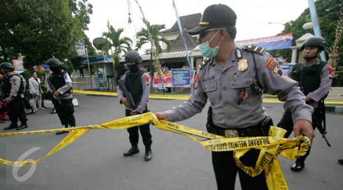 Petugas memasang garis polisi di lokasi bom bunuh diri di Mapolresta Solo, Jawa Tengah, Selasa (5/7). Garis polisi tersebut dipasang mulai dari sisi barat jalan Adi Sucipto menuju sisi timur Jalan KS Tubun. (Liputan6.com/Boy Harjanto)