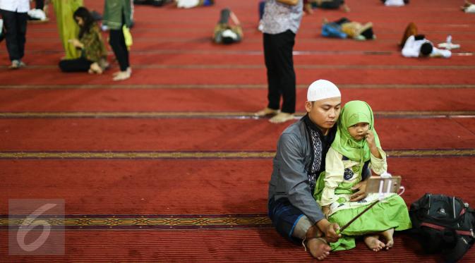 Seorang jemaah berfoto bersama anaknya usai salat Idul Fitri di Masjid Istiqlal, Jakarta, Rabu (6/7). Selain menjalankan salat Idul Fitri, beberapa aktivitas mereka lakukan baik seusai ataupun sebelum salat. (Liputan6.com/Faizal Fanani)