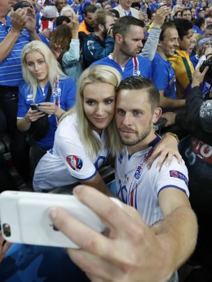 Pemain Islandia, Gylfi Sigurdsson, berwafoto dengan istrinya Alexandra Ivarsdottir usai pertandingan Islandia melawan Prancis di babak perempat final di Stade de France, 3 Juli lalu. (Reuters)