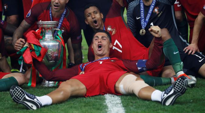 Cristiano Ronaldo berbaring dekat tropi Piala Eropa 2016 usai mengalahkan Prancis 1-0 di Stade de France, Senin (11/7). Ronaldo menjadi pemain Portugal yang tampil paling banyak bersama Portugal yaitu sebanyak 133 penampilan. (REUTERS)