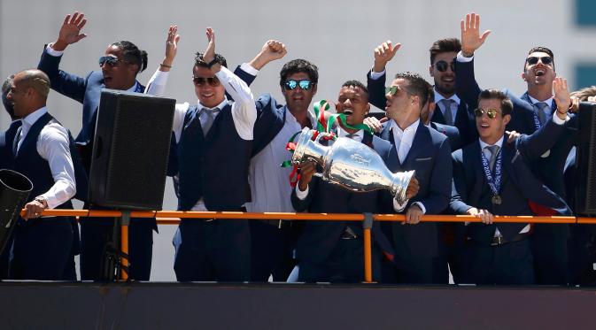 Cristiano Ronaldo dan tim kesebelasan menyapa pendukung mereka di atas bus terbuka saat kembali ke Lisbon, Portugal, Senin (11/7). Portugal menjadi juara Piala Eropa 2016 usai mengalahkan Prancis di final. (REUTERS / Rafael Marchante)