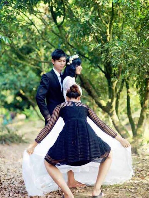 Perjuangan seorang asisten fotografer untuk membuat gaun yang dipakai pengantin wanita terlihat indah di foto, yang tertangkap kamera. Sumber : mymodernmet.com