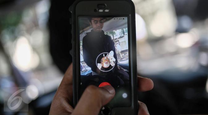 Karakter Pokemon terlihat di dekat seorang pria pada layar smartphone pemain augmented reality game Pokemon Go di Jakarta, Kamis (14/7). Pokemon Go sedang di puncak ketenaran meski baru diluncurkan di beberapa negara. (Liputan6.com/Faizal Fanani)