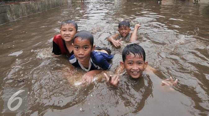 Sejumlah anak di kawasan Kemang Utara memanfaatkan banjir untuk bermain, Jakarta, Rabu (20/7). Akibat intensitas hujan deras yang mengguyur Jakarta, sejumlah ruas jalan tergenang air. (Liputan6.com/Yoppy Renato)