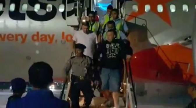 Keenam pria yang berkelahi dikawal turun dari pesawat (The Sydney Morning Herald)