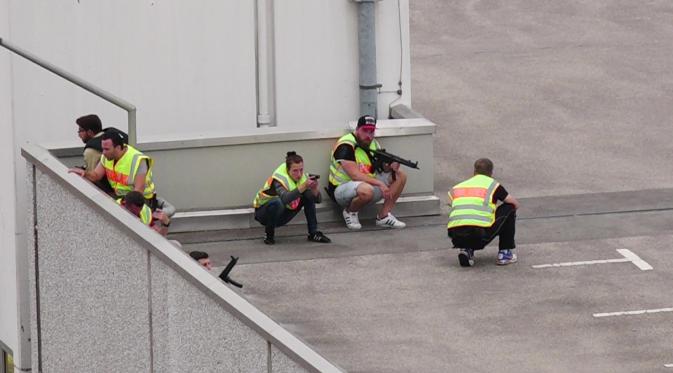  Sejumlah polisi berlindung di tempat parkir pusat perbelanjaan Olympia saat memburu pelaku penembakan di Munich, Jerman (22/7). Aksi teror tersebut membuat panik para pengunjung pusat perbelanjaan tersebut. (dedinac/Marc Mueller/REUTERS)