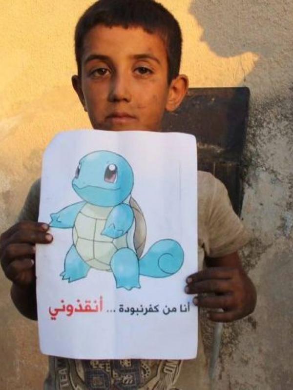 Seorang anak lelaki memegang gambar Squirtle dengan tulisan, "Aku dari Kafr Nabudah, selamatkan aku." (RFS)