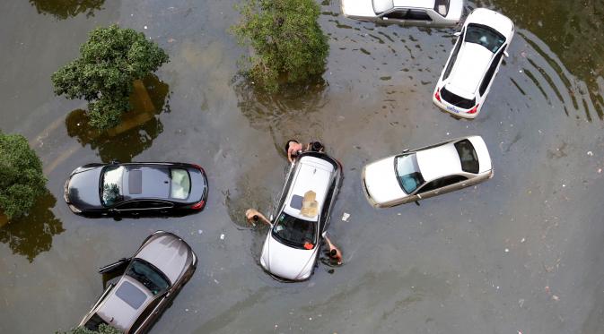 Warga mendorong mobil yang terjebak di area banjir di Wuhan (Reuters)