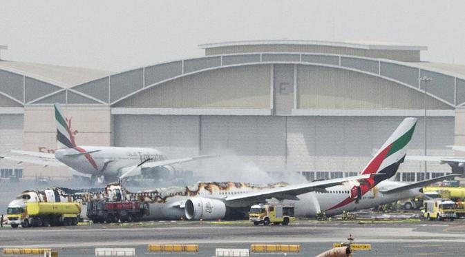 Petugas pemadam kebakaran menyemprotkan air ke pesawat Emirates Airline yang hangus terbakar di Bandara Internasional Dubai, UEA, Rabu (3/8).Kecelakaan ini saat pesawat mencoba mendarat. (Reuters)