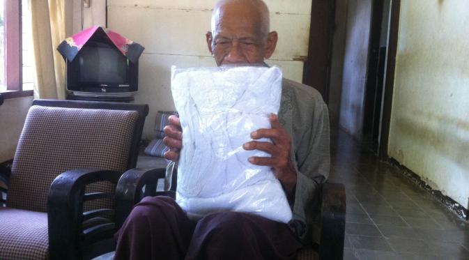 Kakek Ambari memegang kain ihram pemberian tetangganya. (Liputan6.com/Panji Prayitno)
