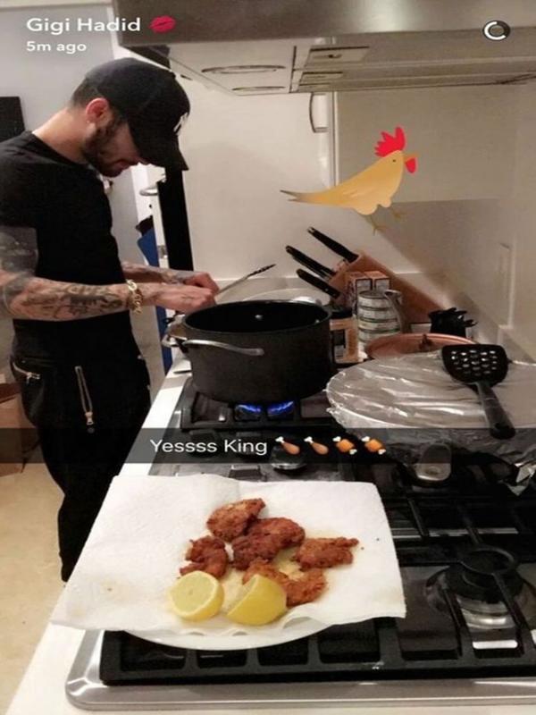 Pada kesempatan yang itu, Zayn Malik mengenakan kaus hitam dan memakai topi cap berwarna senada tengah serius memasak di tempat tinggalnya bersama Gigi. (Snapchat)
