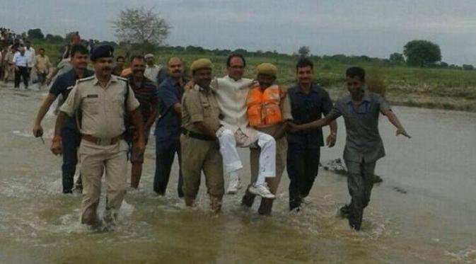 Menteri dari negara Madhya Pradesh, Shivrah Singh Chauhan tertangkap kamera tengah dibopong dalam kunjungannya ke daerah yang dilanda banjir (BBC/@AtrangiLekhak)