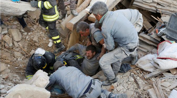 Sejumlah petugas dibantu warga menolong seorang pria yang tertimbun reruntuhan bangunan akibat gempa di Amatrice, Italia tengah, (24/8). Sekitar enam orang tewas akibat gempa tersebu. (REUTERS/Remo Casilli)