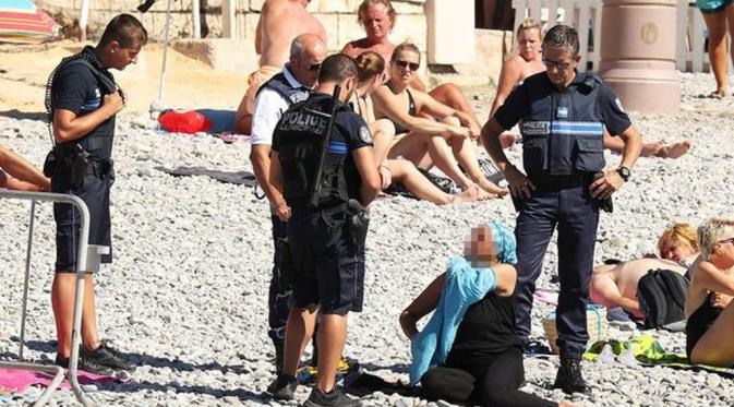 Polisi Perancis menyuruh turis muslim yang memakai burkini untuk membukanya. (via: theguardian)