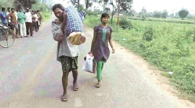 Dana Majhi (kiri), menggendong jenazah istrinya dan berjalan hingga 12 km menuju desa untuk dikremasi. Dana Majhi, didampingi putrinya yang terus menangis sepanjang jalan. Foto : indianexpress.