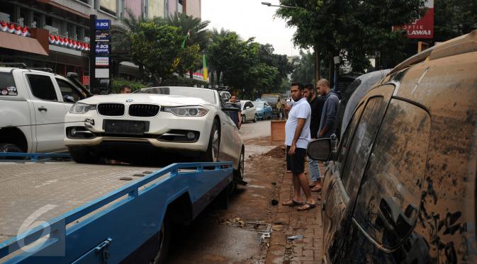 Sebuah mobil mewah dievakuasi setelah terjebak banjir di basement sebuah pertokoan di Jalan Kemang Raya, Minggu (28/8). Sejumlah kendaraan terendam air di kawasan Kemang pasca hujan deras di Jakarta, Sabtu (27/8). (Liputan6.com/Helmi Fithriansyah)