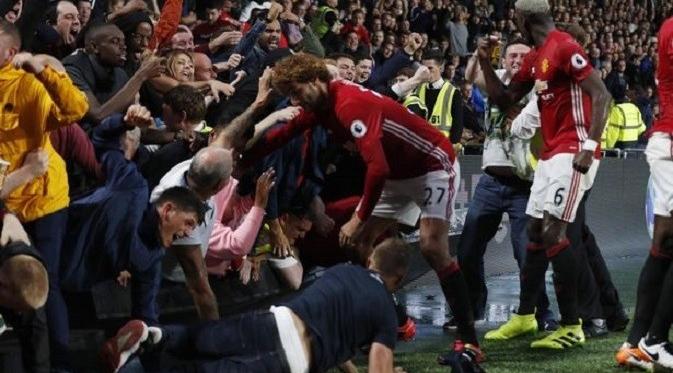 Marouane Fellaini tak ikut merayakan gol telat Marcus Rashford ke gawang Hull City karena sibuk menyelamatkan seorang fans yang terjebak. (Reuters)