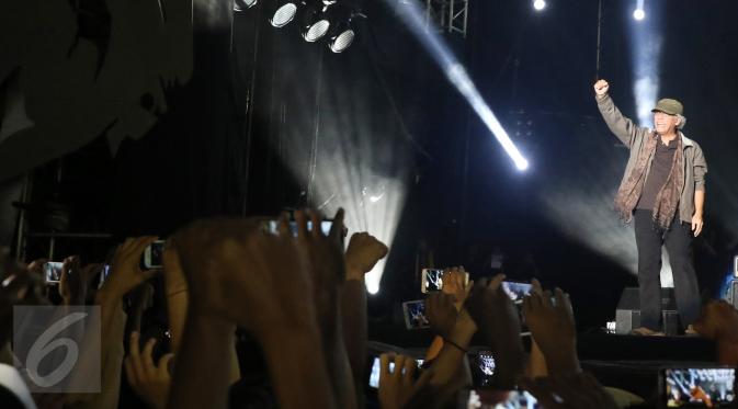 Musisi Iwan Fals menyapa para penonton pada konser Perayaan Karya Iwan Fals di Pantai Carnaval Ancol, Jakarta, Sabtu (03/9). Konser tersebut sebagai bentuk apresiasi dari perjalanan karir sang Iegenda musik Indonesia. (Liputan6.com/Herman Zakharia)