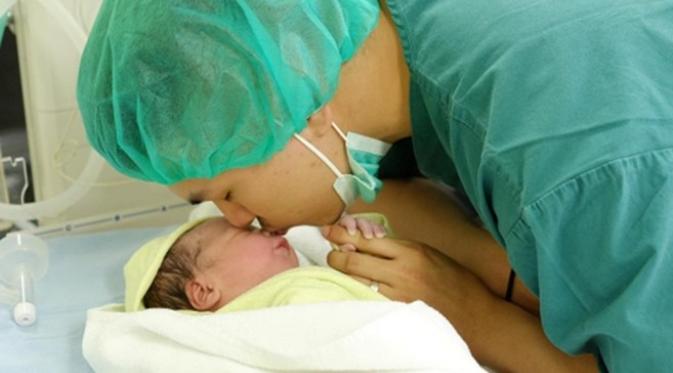 Glenn Alinskie mencium putri pertamanya, Nastusha Olivia Alinskie yang baru lahir. (Instagram @glennalinskie)
