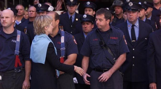 Hillary menyalami pasukan pemadam kebakaran saat menghadiri pemakaman salah satu komandan mereka (Reuters)