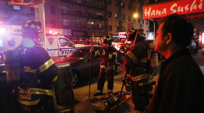 Petugas melakukan penyelidikan di lokasi terjadinya ledakan di New York, Sabtu (17/9). Diduga ledakan terjadi di tempat sampah, menghancurkan jendela gedung yang berada di dekatnya. (AFP PHOTO)