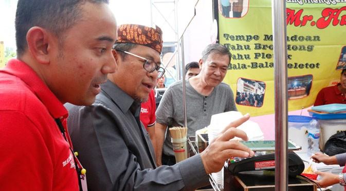 Gubernur Jawa Barat Ahmad Heryawan didampingi Manager Branch Bandung Telkomsel Saki Brahmono saat menggunakan TCASH Tap Telkomsel. (Istimewa)
