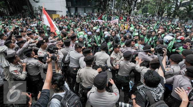 Massa driver Gojek terlibat aksi saling dorong dengan polisi saat demo ke kantor pusat mereka di Kemang, Senin (3/10). Ratusan pengemudi Gojek itu menuntut penghapusan sistem performa atau rating. (Liputan6.com/Yoppy Renato)