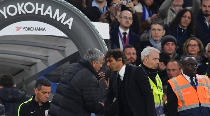 Manajer Manchester United (MU), Jose Mourinho, terlihat berbisik kepada manajer Chelsea, Antonio Conte, seusai pertandingan kedua tim, di Stamford Bridge, Minggu (23/10/2016). (AFP/Glyn Kirk).
