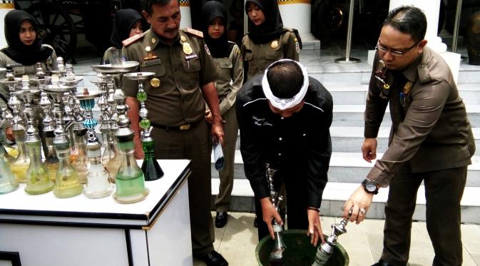 Bupati Dedi Mulyadi bersama Satpol PP Kabupaten Purwakarta menghancurkan barang bukti hasil razia berupa alat isap rokok shisha. (Liputan6.com/Abramena)